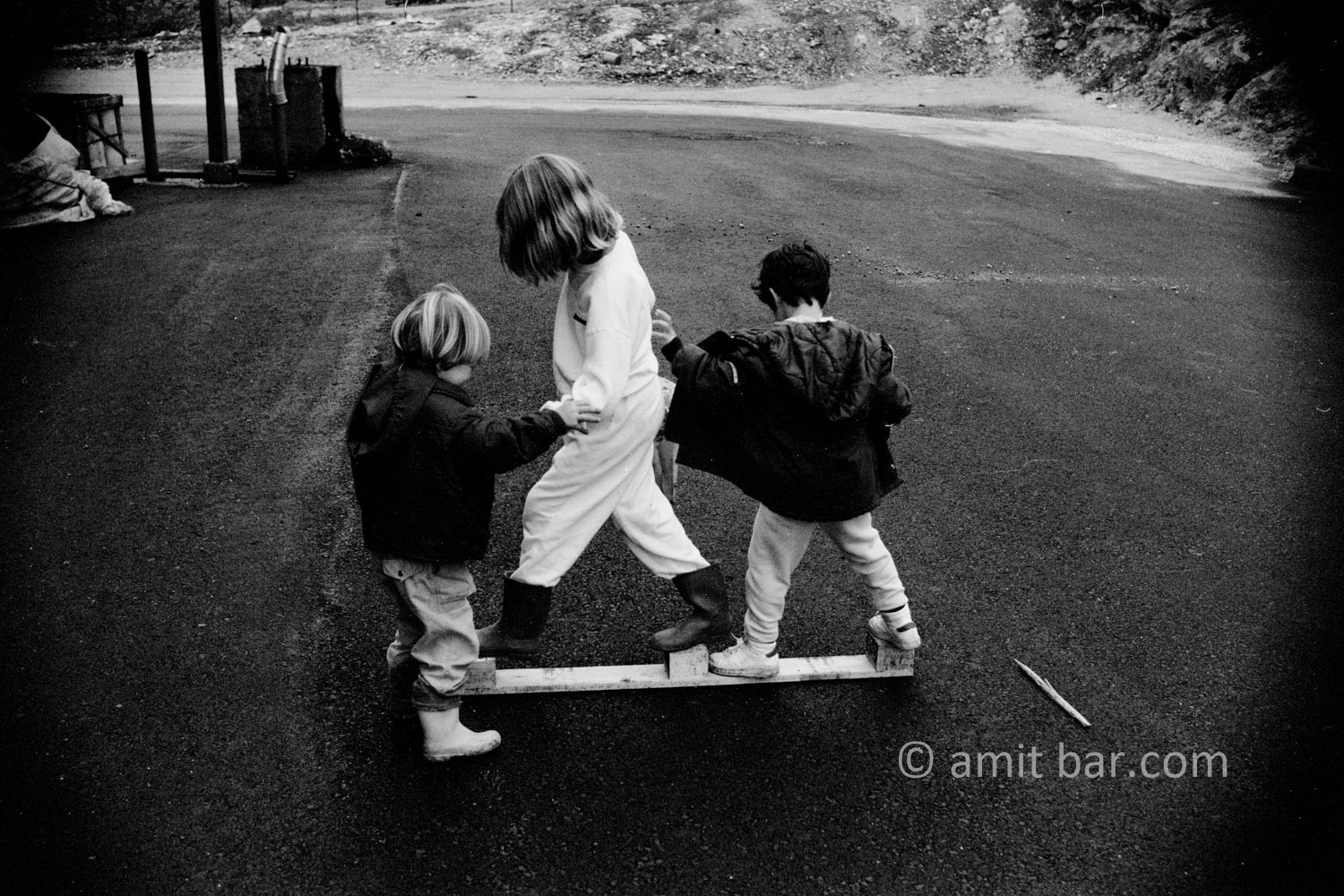 Balancing: Three children are searching a balance on a wooden plank