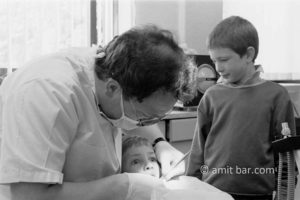 Big eyes: A boy on dentist 's chair, while his brother watching