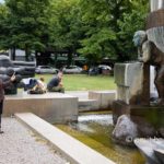 Can I help, you, Miss?: A woman is taking a photo of sculpture