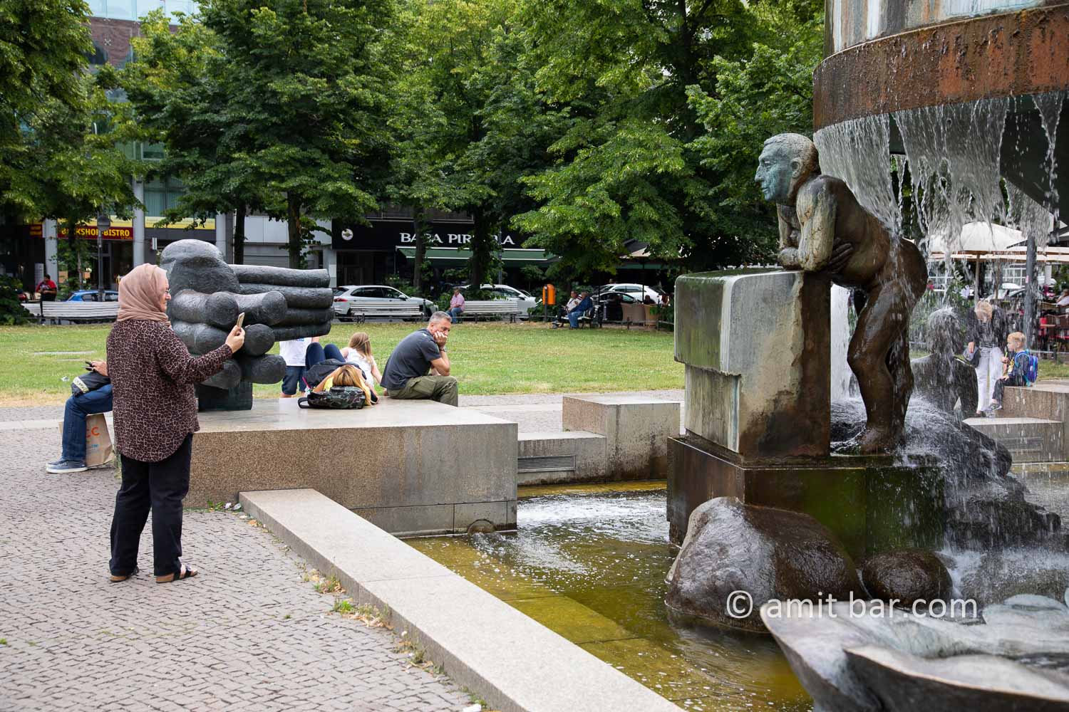 Can I help, you, Miss?: A woman is taking a photo of sculpture