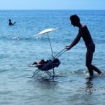 Cooling down: A man is pushing his baby-trolley in sea-water