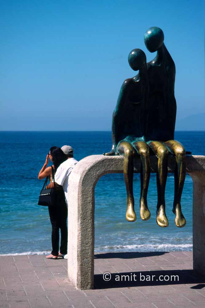 Couples: A sculpture couple looking to a real couple on the promenade of Puerto Vallarta, Mexico
