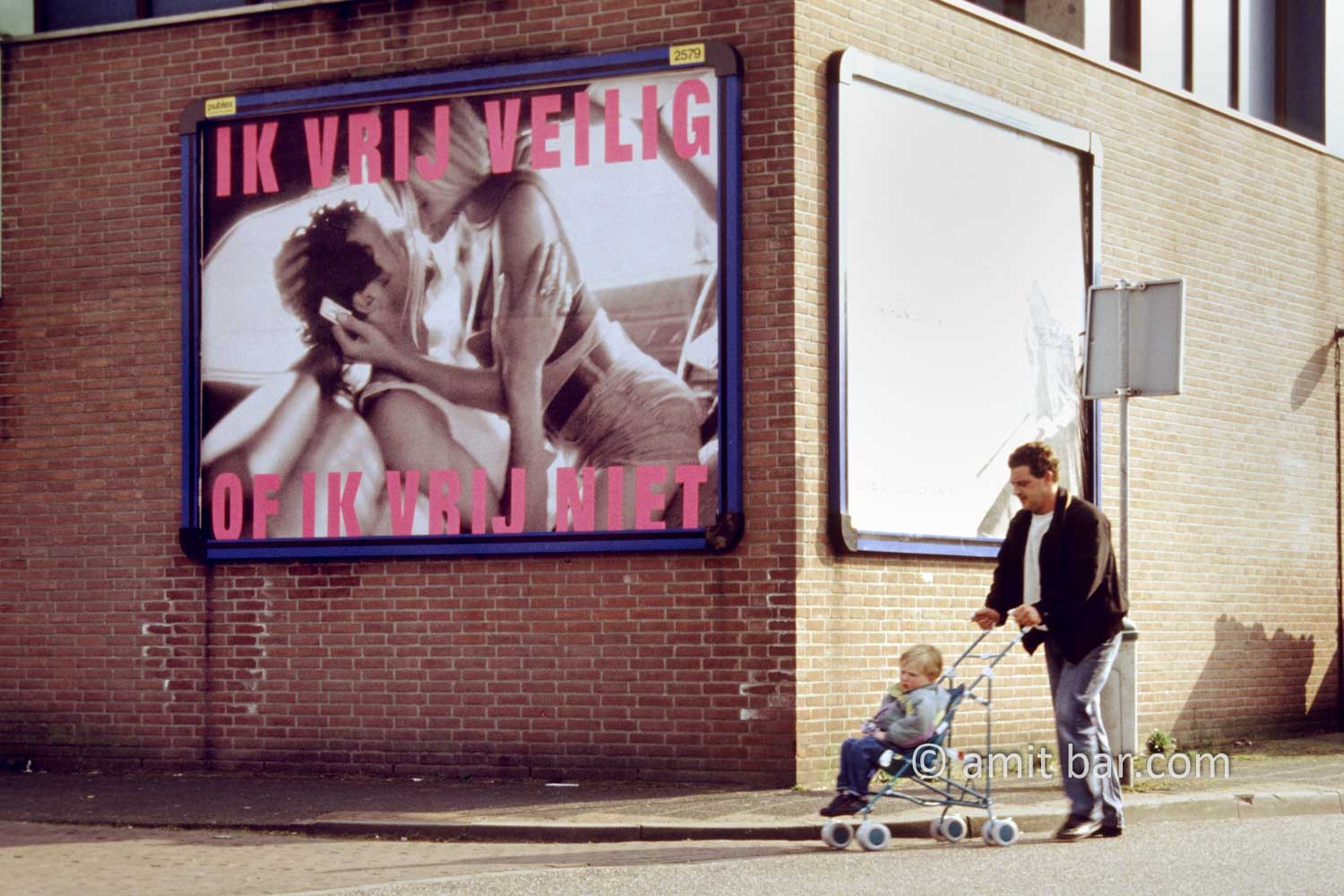 I make love safely, or I don't make love: A man with his toddler in a buggy is passing besides the billboard: "I make love safely, or I don't make love".