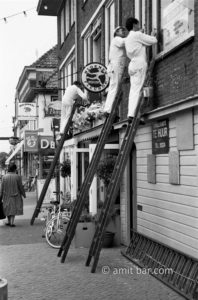 On the ladder: Three painters are working on ladders beside the Interflora courier. Doetinchem, The Netherlands