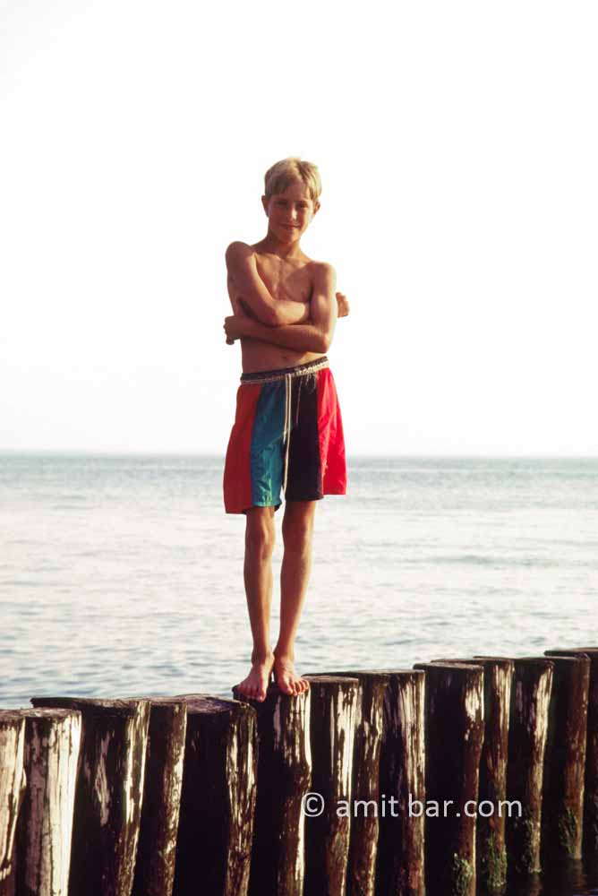 Ready to jump I: A boy is standing on pillars at the sea