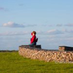 Red coat: Woman with red coat on srone hedge