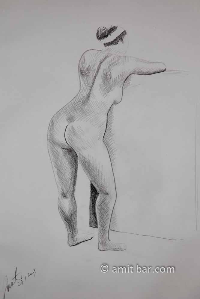 Standing model seen from behind leaning on a high box. Pencil drawing
