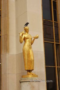 Three pigeons: A pigeon sits on golden sculpture with two pigeons